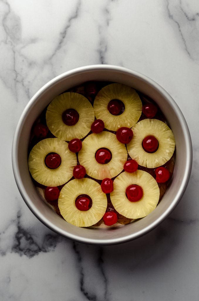 Aerial photo of the pineapple and cherry layer in the bottom of a pan to make pineapple upside down cheesecake.