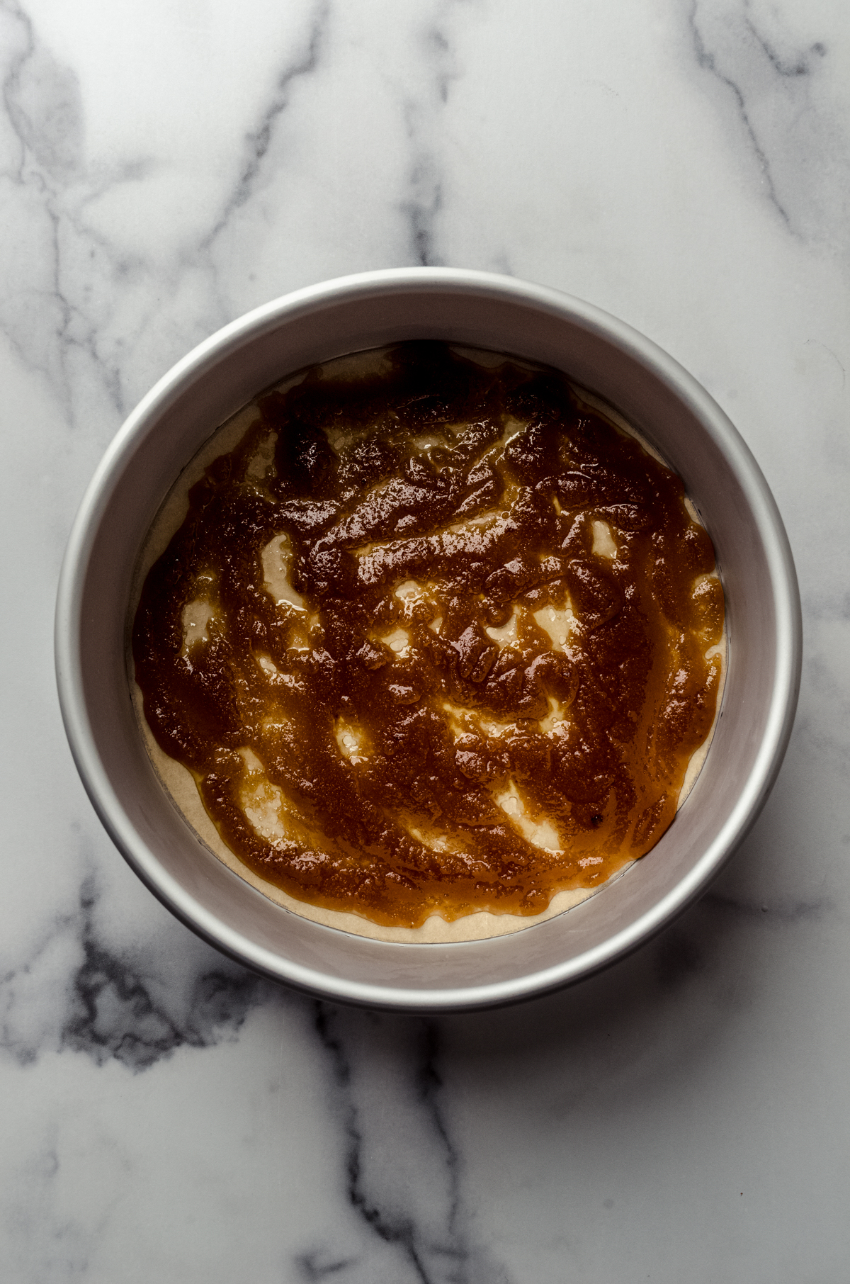 Aerial photo of the brown sugar and butter layer in the bottom of a pan to make pineapple upside down cheesecake.