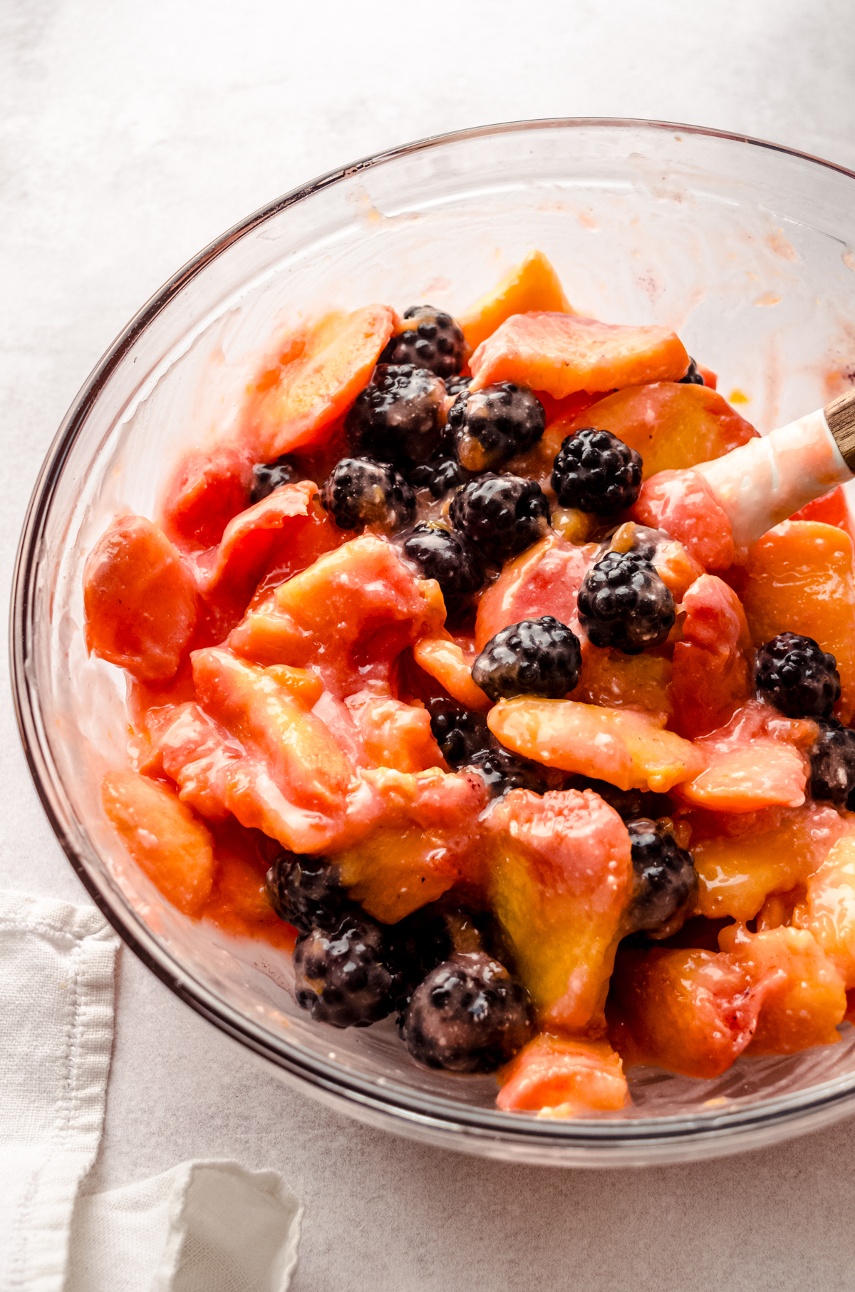 The filling for blackberry peach pie in a large bowl with a spatula.