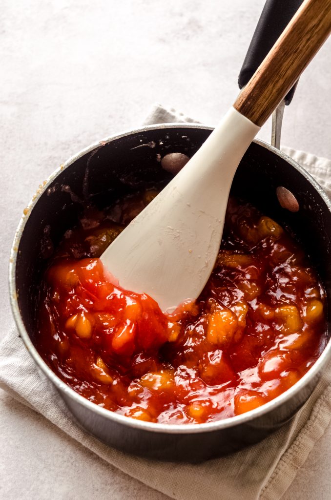 Peaches in a saucepan with a spatula ready to make peach blackberry pie.