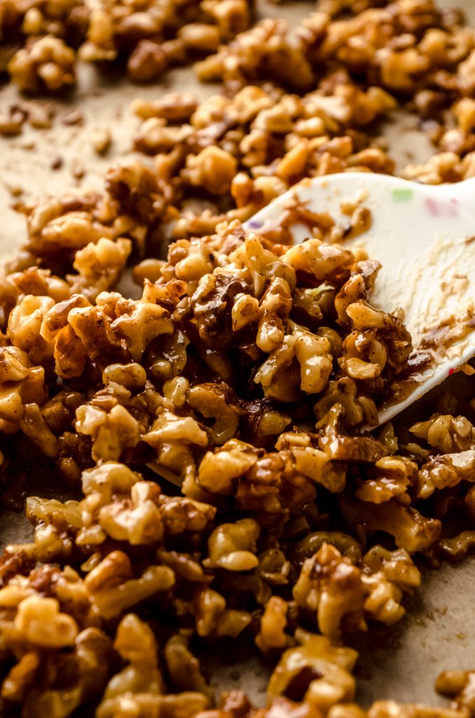 A honey walnut mixture on a baking sheet with a spatula.