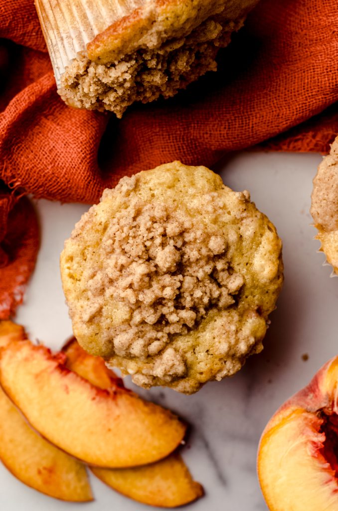 Aerial photo of a peach streusel muffin on a surface.