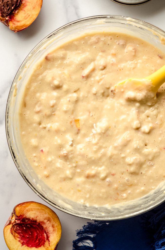 Peach muffin batter in a large bowl with a spatula.