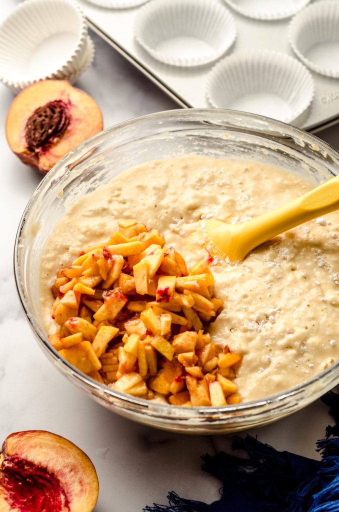 Peach muffin batter in a large bowl with a spatula.