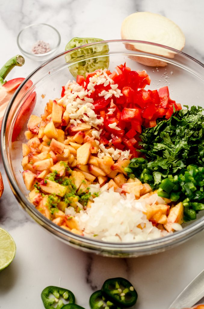 Ingredients to make peach salsa in a bowl.