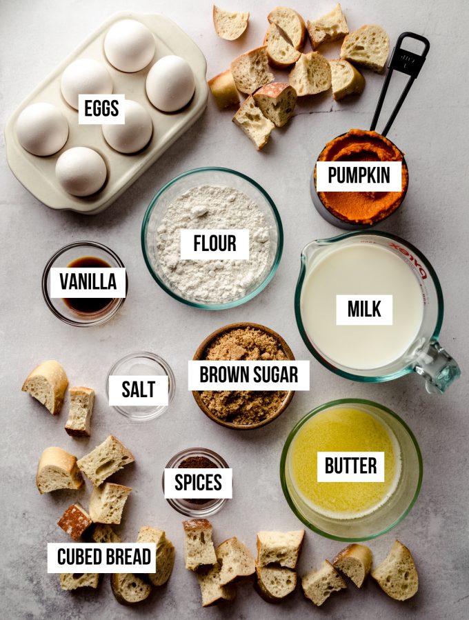 Aerial photo of ingredients to make pumpkin French toast casserole with text overlay labeling each ingredient.