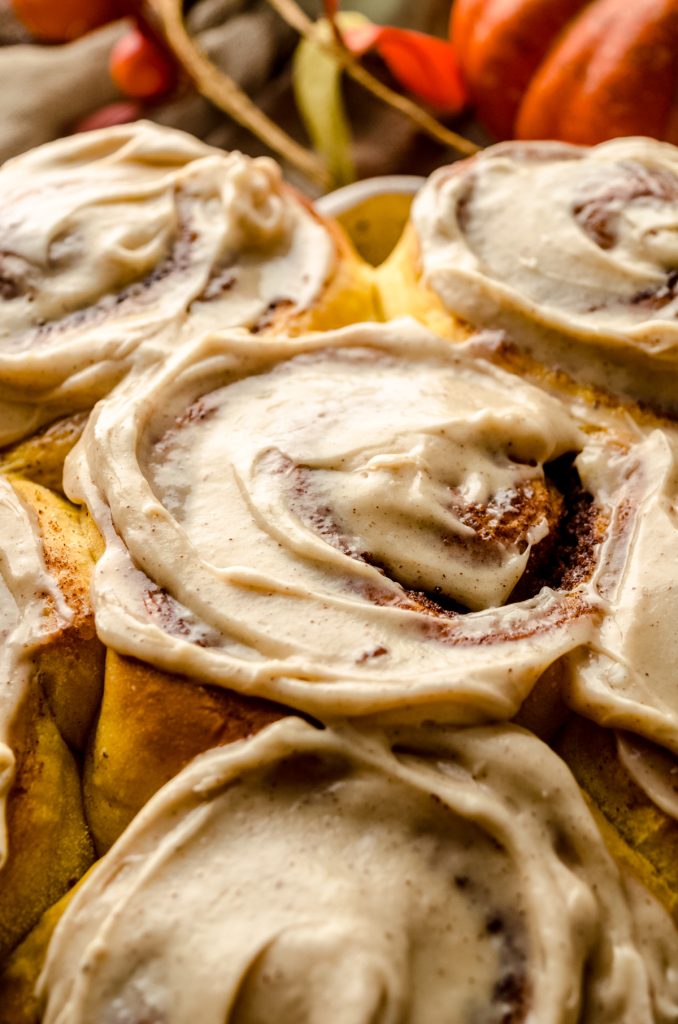 Pumpkin cinnamon rolls topped with maple cinnamon cream cheese frosting.