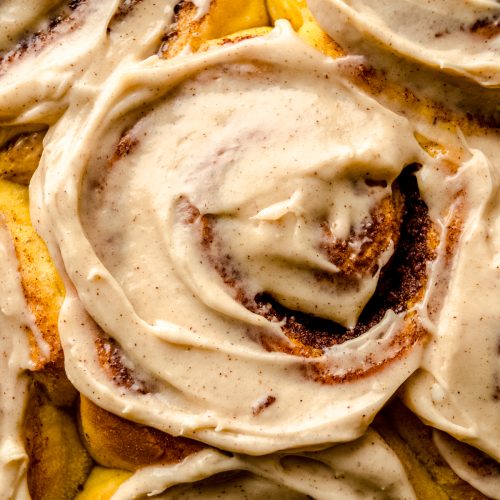 Aerial photo of pumpkin cinnamon rolls topped with maple cinnamon cream cheese frosting.