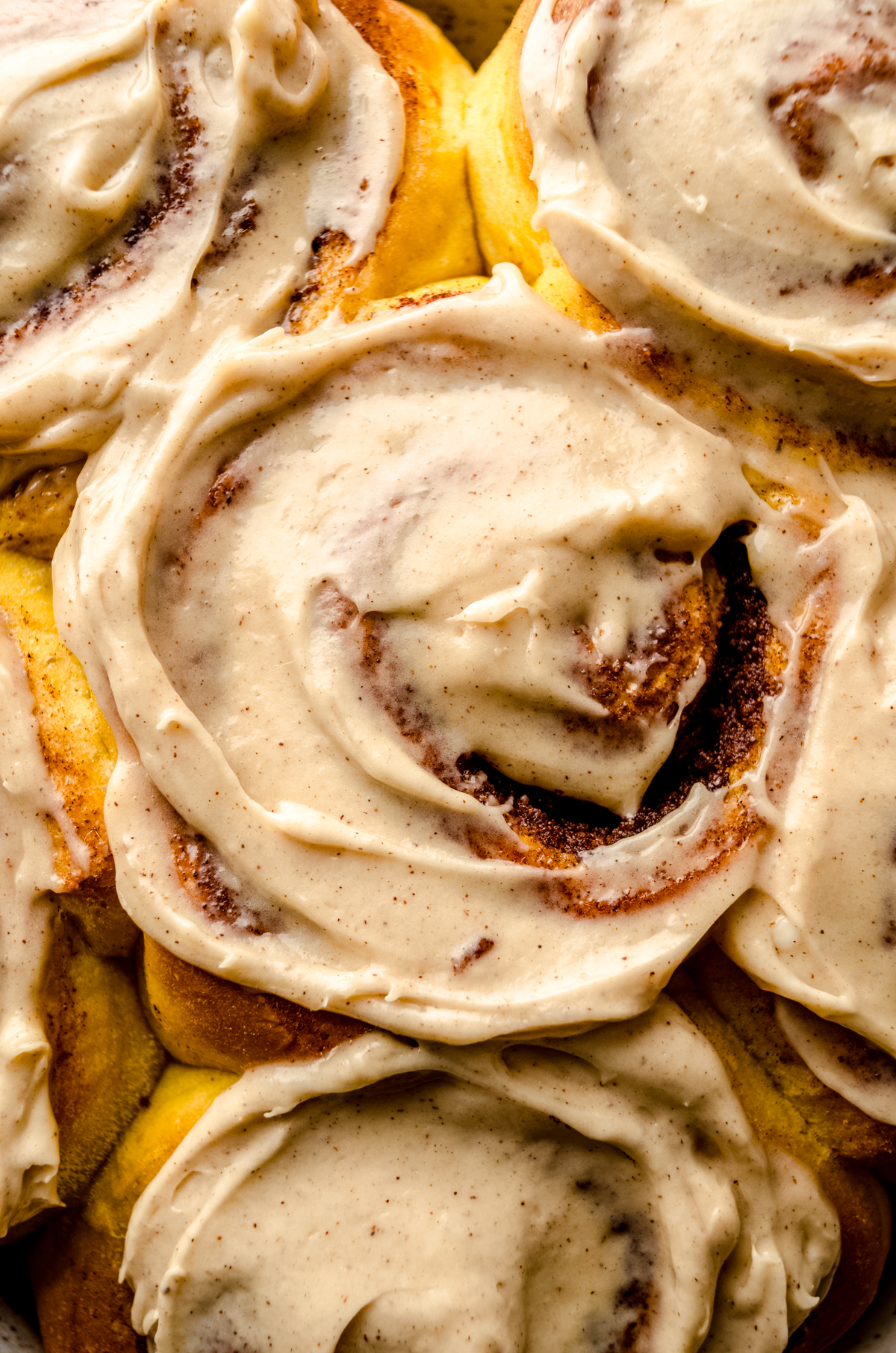 Aerial photo of pumpkin cinnamon rolls topped with maple cinnamon cream cheese frosting.