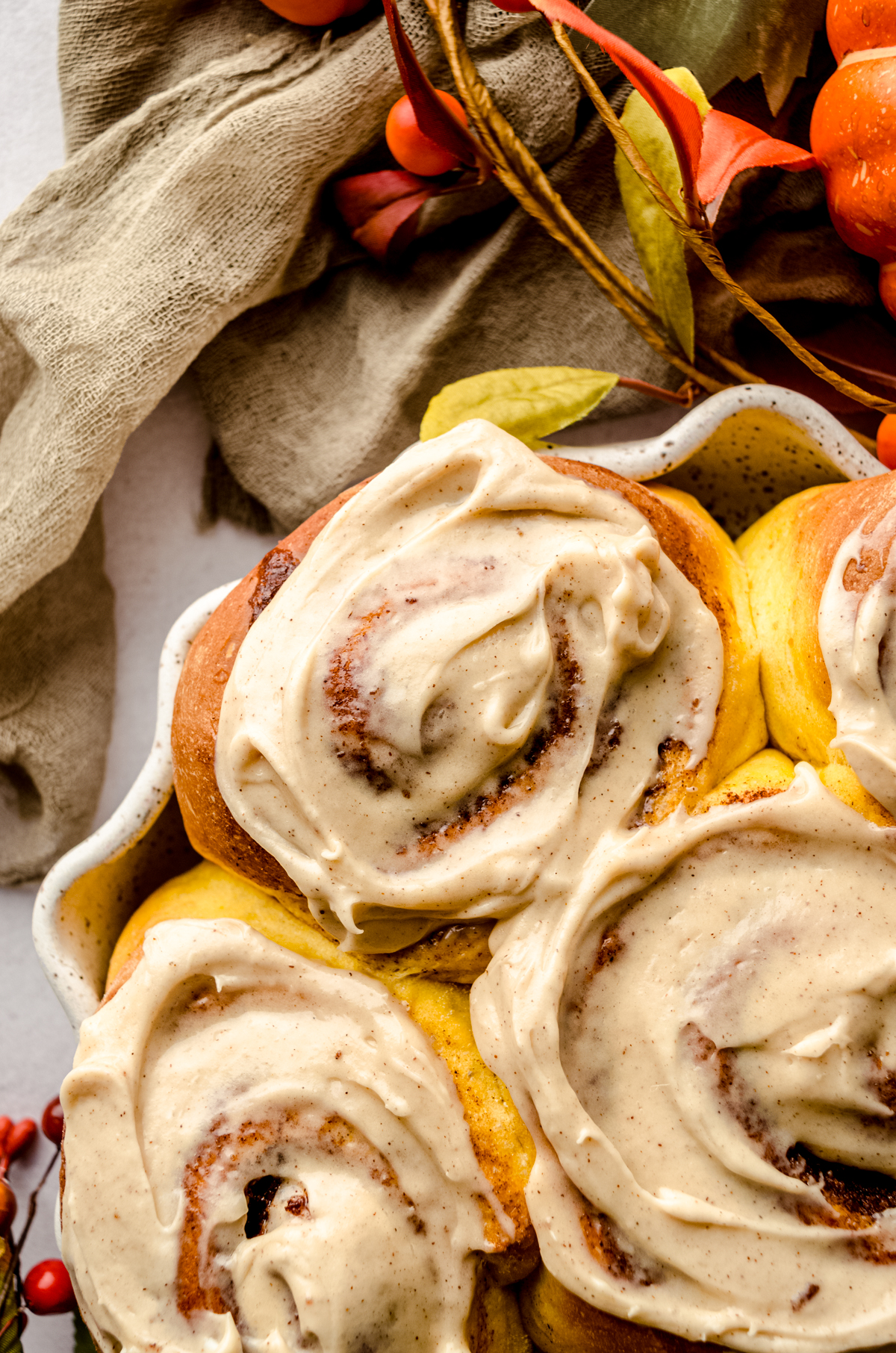 Aerial photo of pumpkin cinnamon rolls topped with maple cinnamon cream cheese frosting.