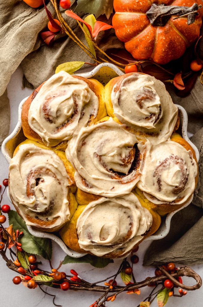 Aerial photo of pumpkin cinnamon rolls topped with maple cinnamon cream cheese frosting.