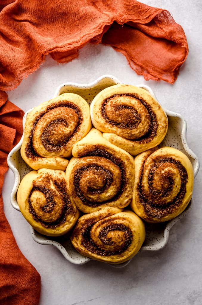 Pumpkin cinnamon rolls in a baking dish after rising.