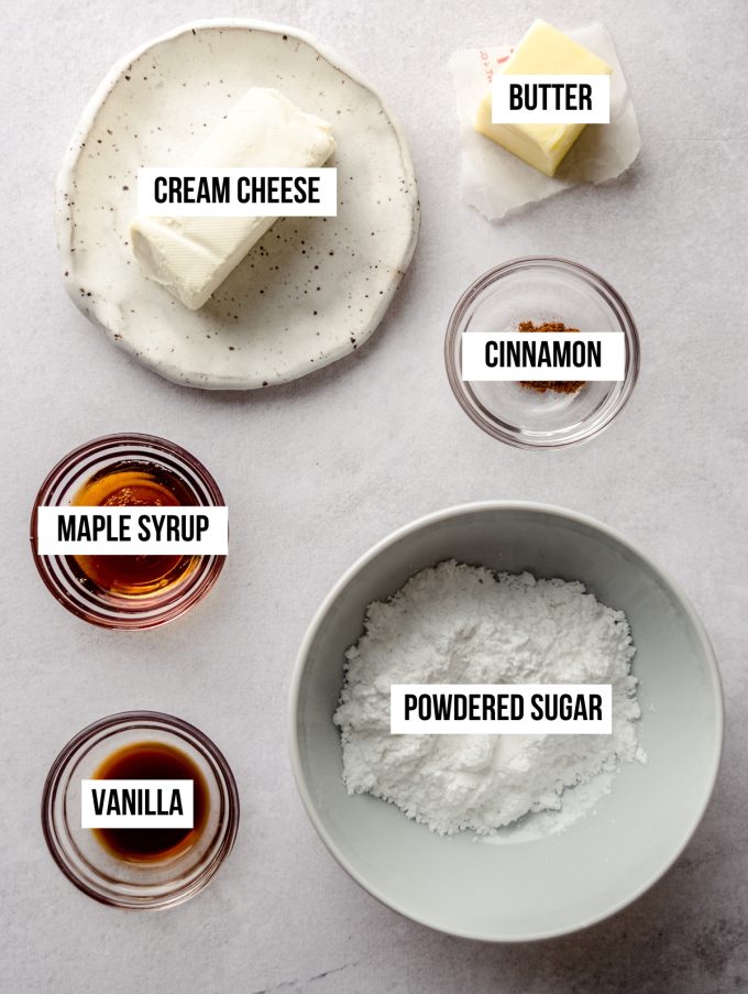 Aerial photo of ingredients to make maple cinnamon cream cheese frosting with text overlay labeling each ingredient.