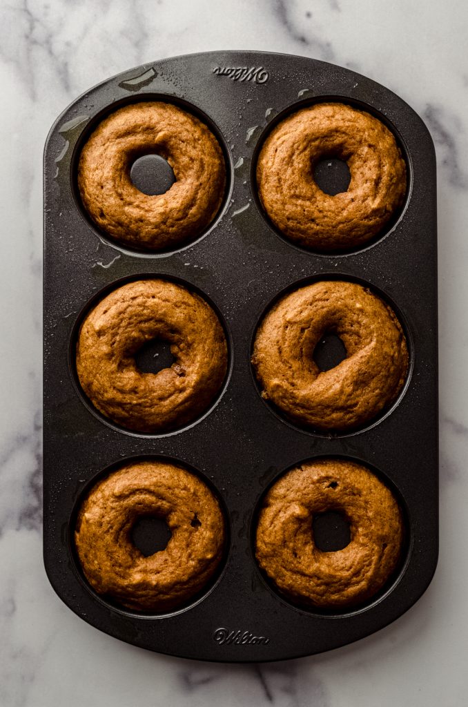 Aerial photo of a donut pan with baked pumpkin donuts in it.