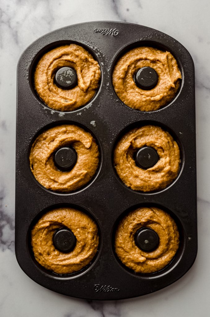 Aerial photo of a donut pan filled with pumpkin donut batter.