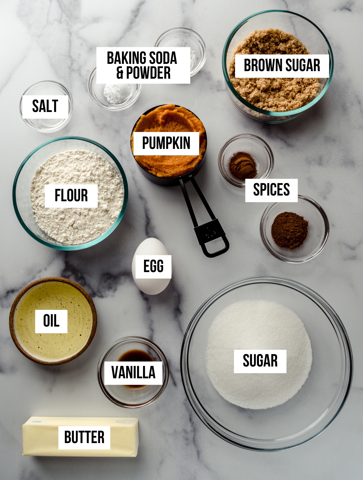 Aerial photo of ingredients to make baked pumpkin donuts with text overlay labeling each ingredient.