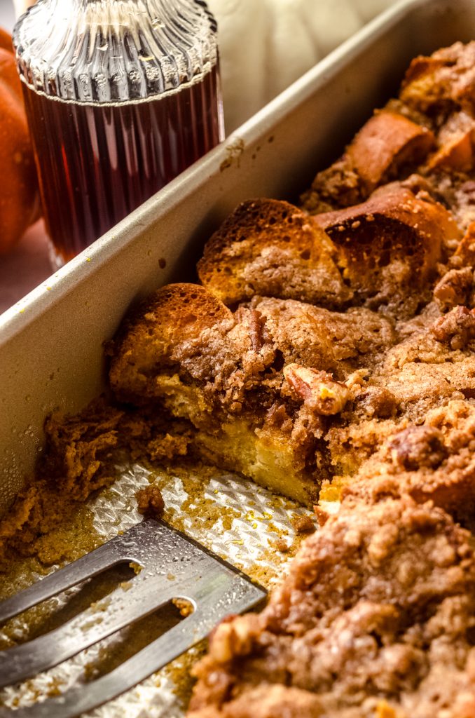 Pumpkin French toast casserole in a casserole dish with a slice taken out of it.