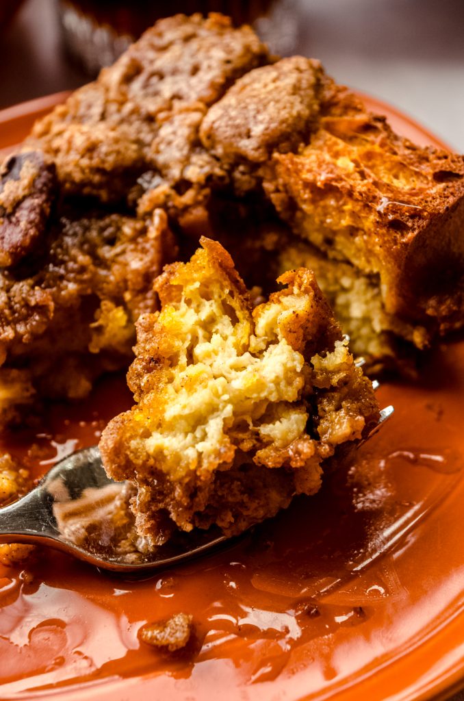 A photo of pumpkin French toast casserole on a plate with a fork that has a bite of food on it.