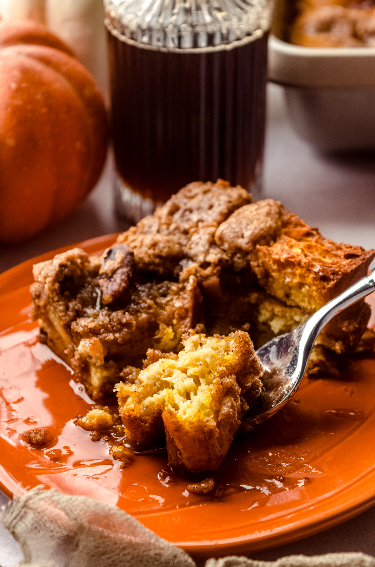 A photo of pumpkin French toast casserole on a plate with a fork that has a bite of food on it.