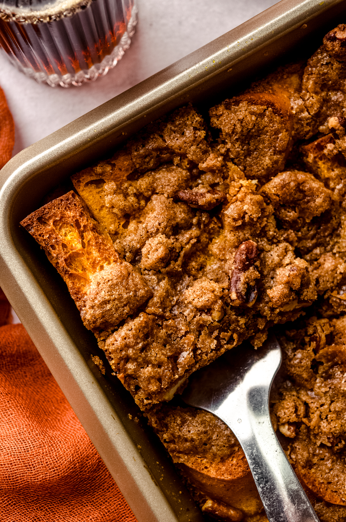 Aerial photo of someone lifting a slice of pumpkin French toast casserole out of a baking dish.