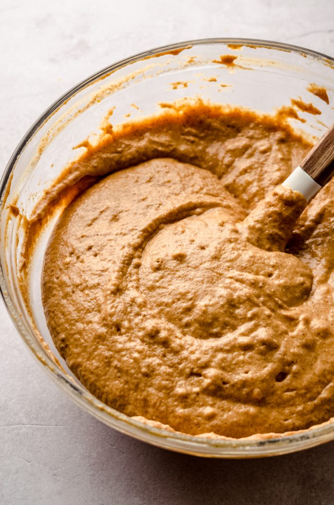 The batter for pumpkin pancakes in a bowl with a spatula.