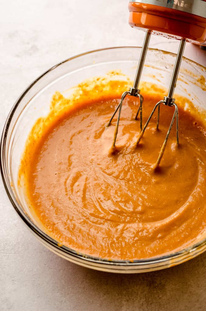 The batter for pumpkin pancakes in a bowl with a handheld mixer.