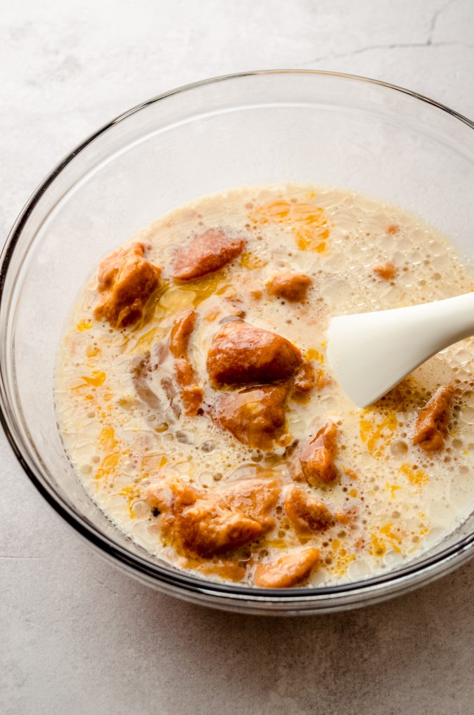 A bowl of the ingredients to make pumpkin pancakes in a bowl with a spatula.