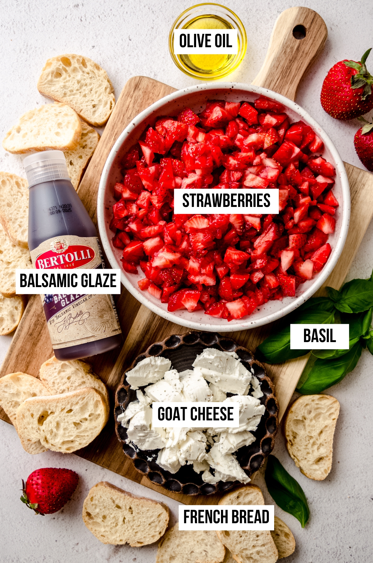 Aerial photo of ingredients to make strawberry goat cheese bruschetta with text overlay labeling each ingredient.