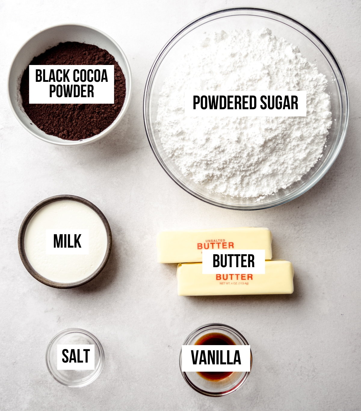 Aerial photo of ingredients to make black cocoa chocolate frosting with text overlay labeling each ingredient.