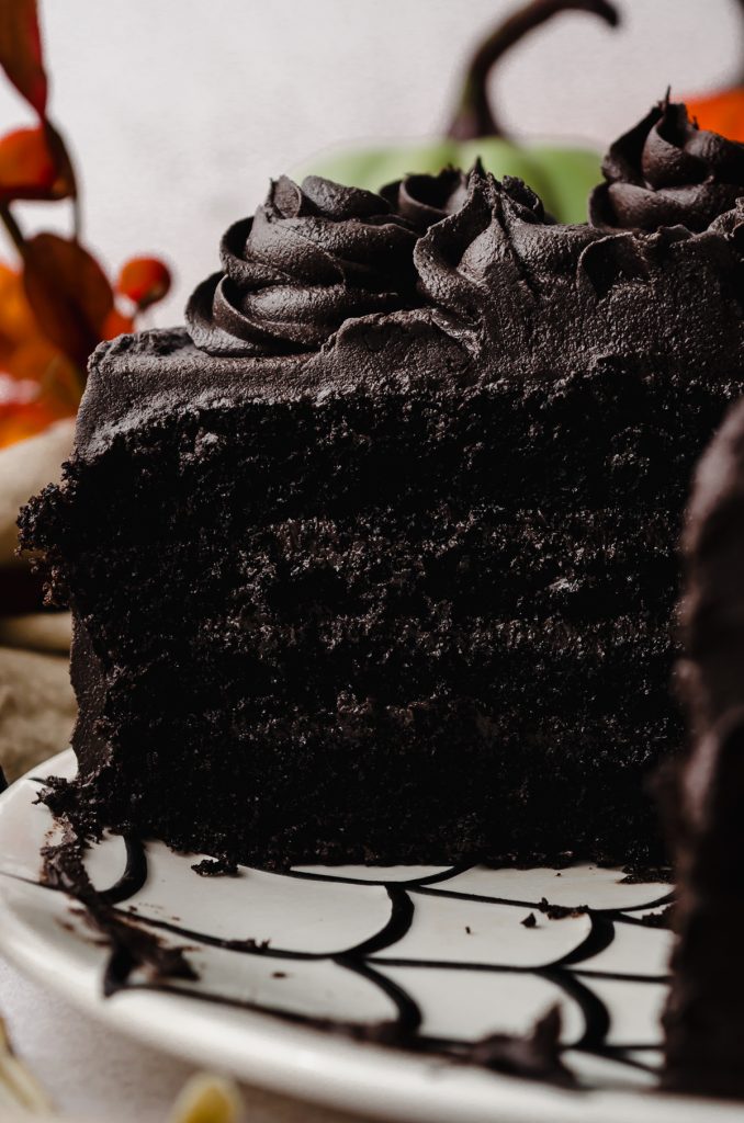 A black cocoa chocolate cake that has been cut so you can see the cross section sitting on a plate.