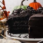 A black cocoa chocolate cake that has been cut so you can see the cross section sitting on a plate.