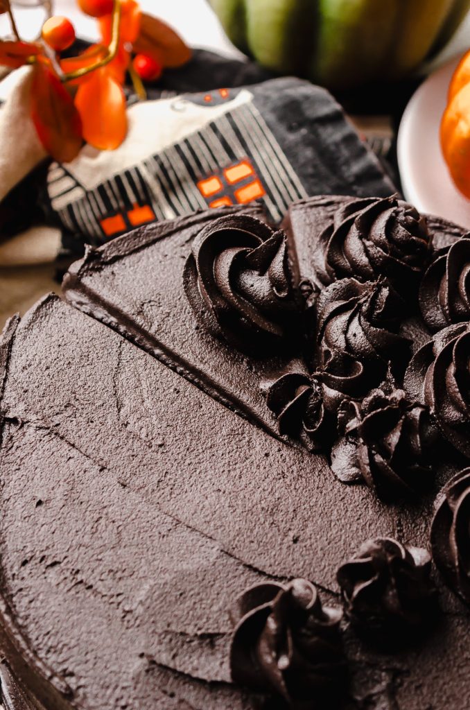 A chocolate Halloween cake on a plate and slice marks have been made.