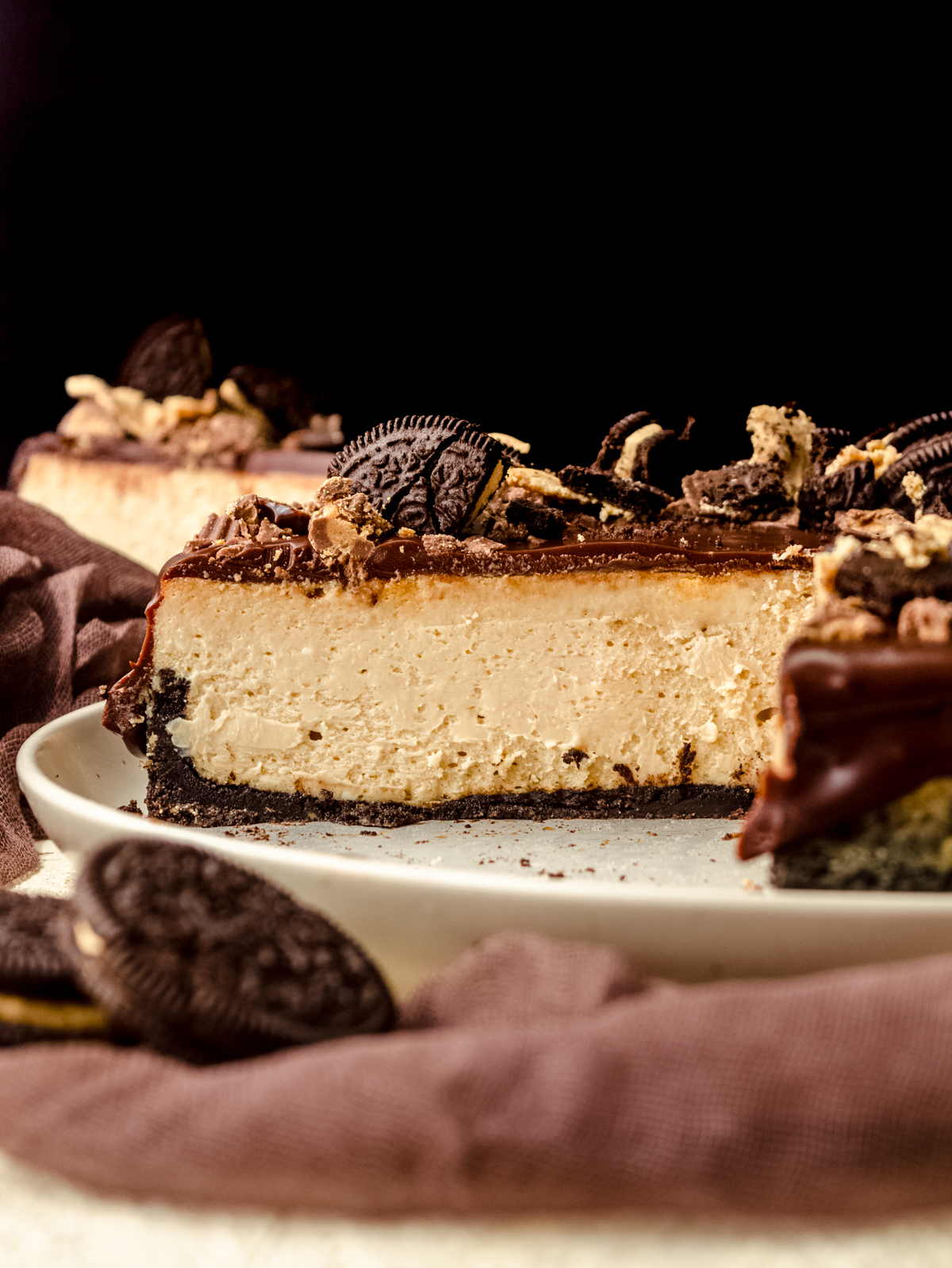 A chocolate peanut butter cheesecake on a plate and a slice has been removed so you can see the cross section.