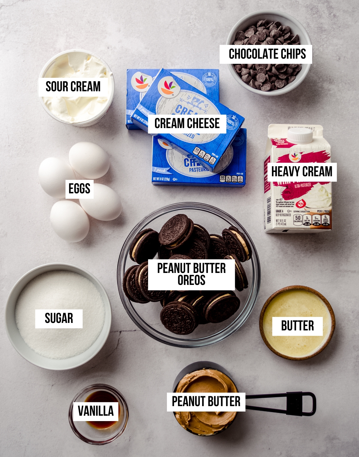 Aerial photo of ingredients to make a chocolate peanut butter cheesecake with text overlay labeling each ingredient.