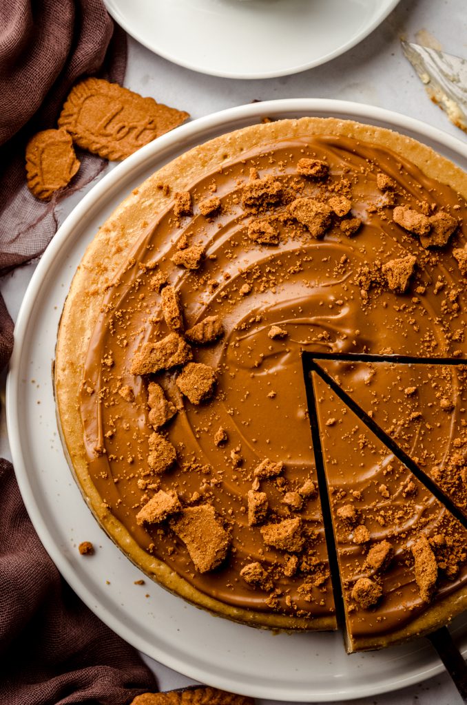 Aerial photo of a Biscoff cheesecake on a plate and it has been sliced.