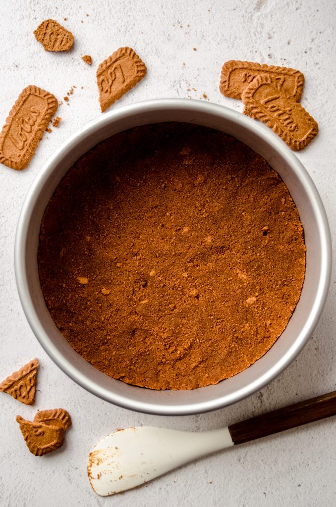 Aerial photo of a Biscoff crust in a round pan to make Biscoff cheesecake.