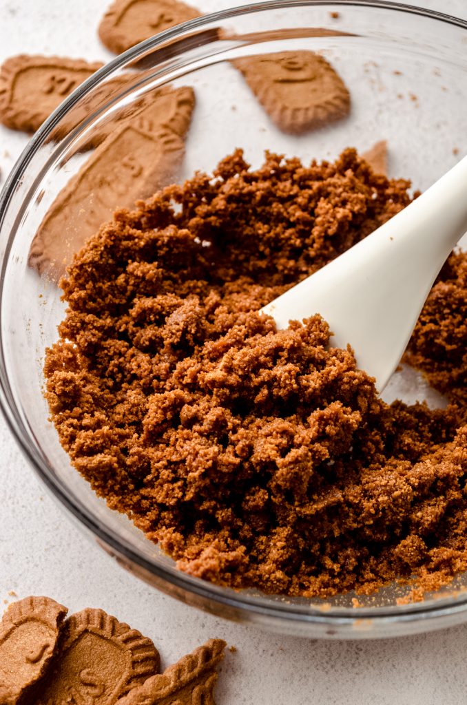 A bowl of crushed Biscoff cookies with a spatula in it.