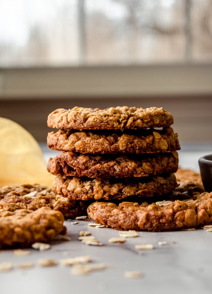 A stack of oatmeal cookies on a surface with a windowsill in the background.