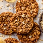 Aerial photo of chewy oatmeal cookies on a surface with oats scattered around.