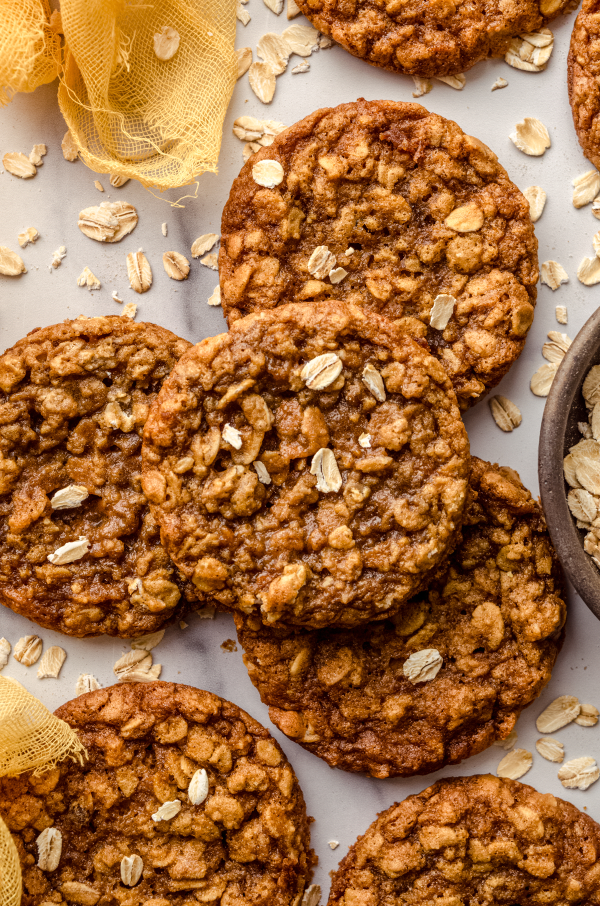 Aerial photo of chewy oatmeal cookies on a surface with oats scattered around.