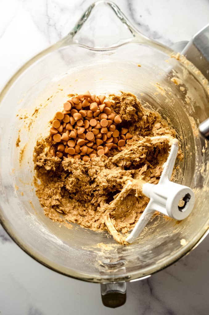 Aerial photo of a bowl of oatmeal scotchies cookie dough with butterscotch chips in the bowl ready to be mixed in.