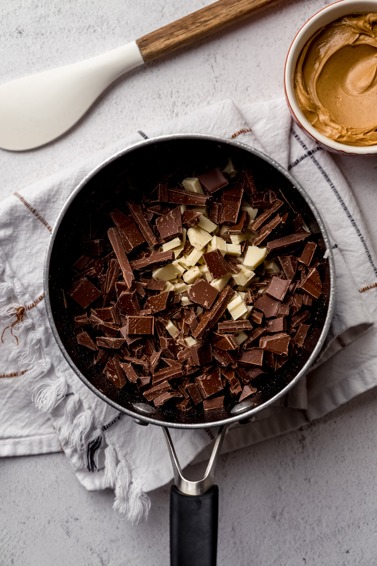 Aerial photo of a saucepan with chopped white and milk chocolate pieces in it.