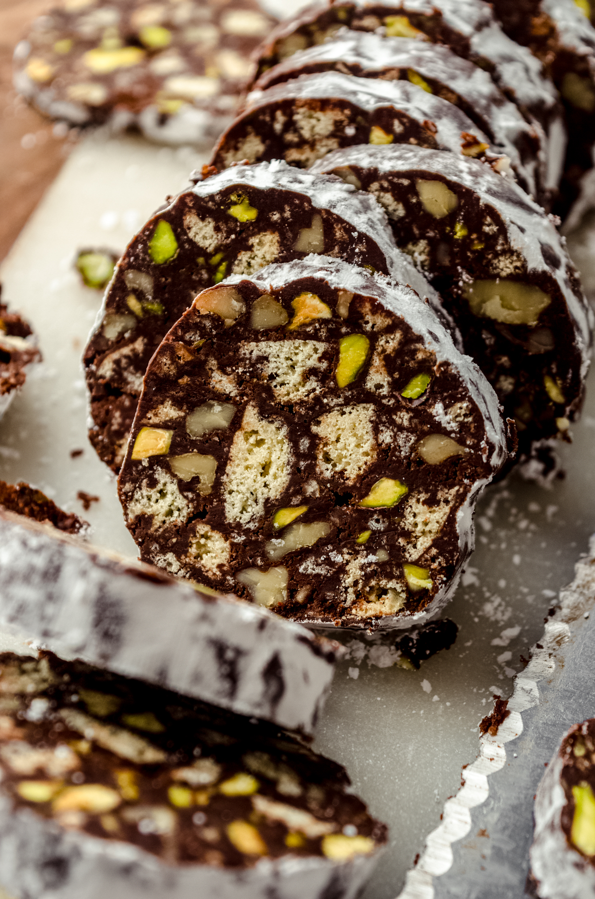 A log of chocolate salami that has been sliced and is sitting on a cutting board.