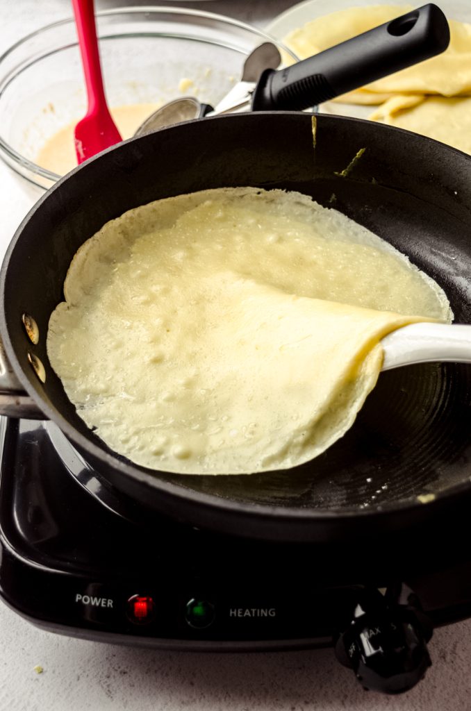 Someone is using a spatula to flip a crepe.