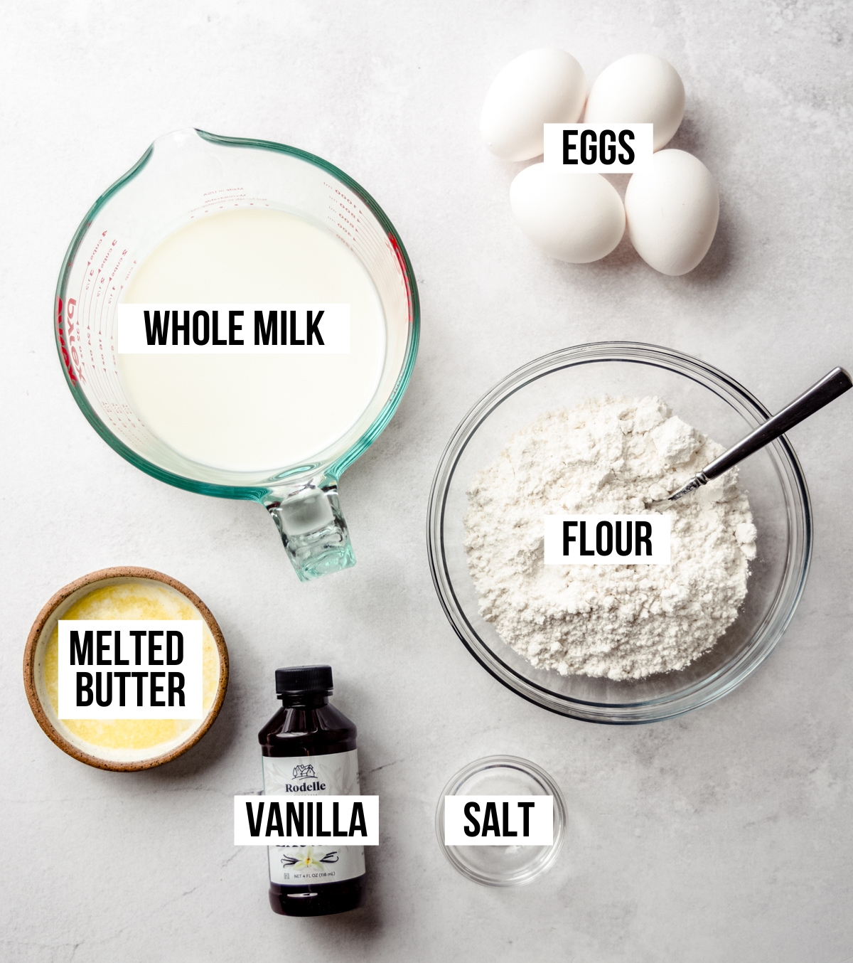 Aerial photo of ingredients to make homemade crepes with text overlay labeling each ingredient.