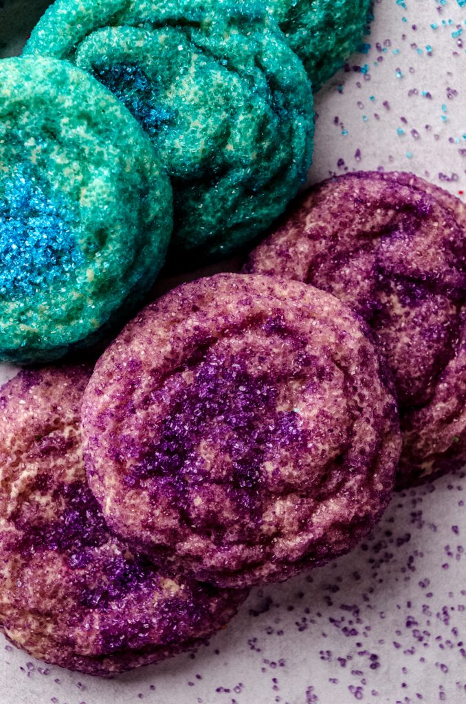 Blue and purple sugar cookies on a surface.