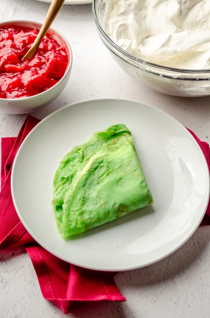 A green crepe folded into a triangle on a plate.