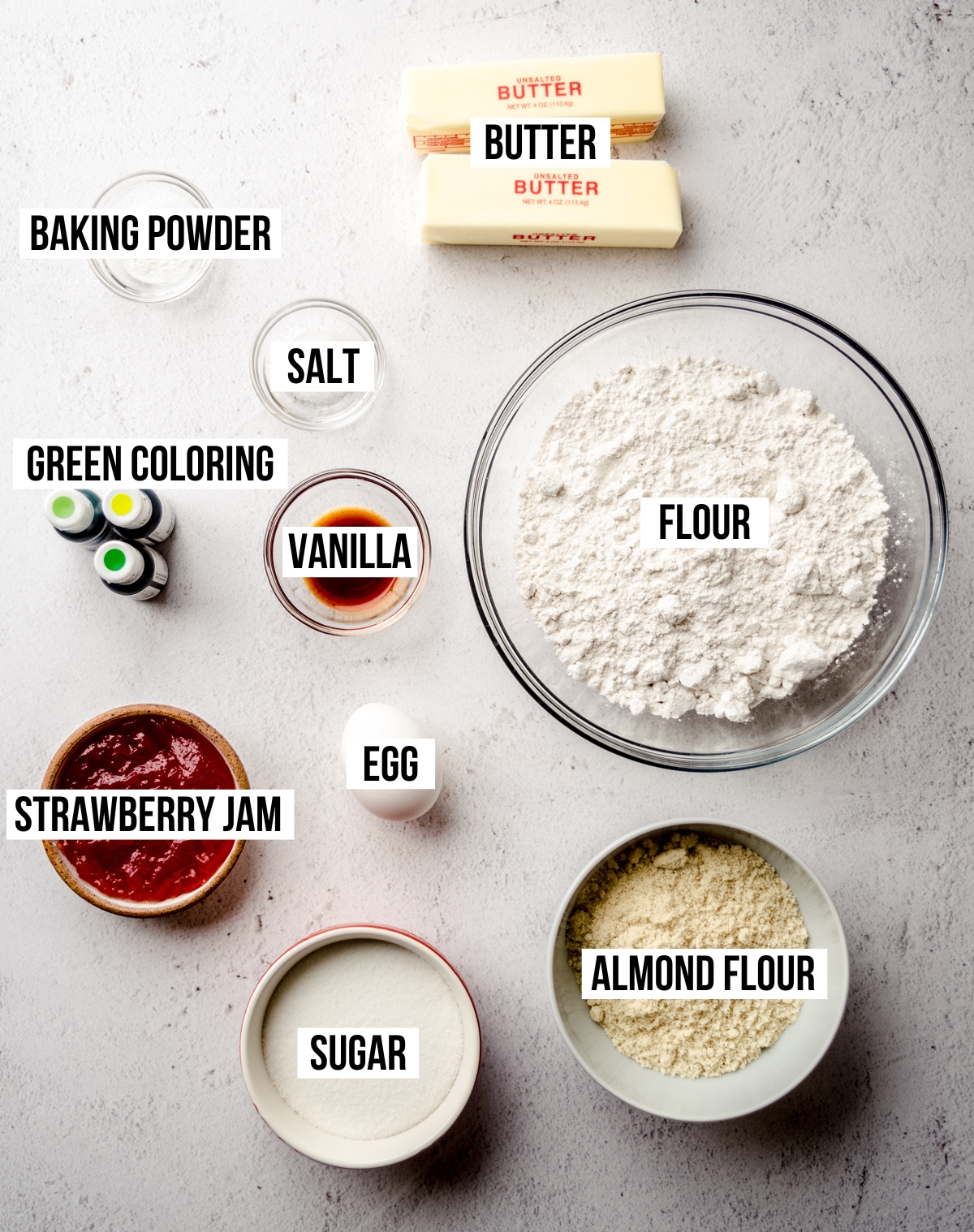 Aerial photo of ingredients to make Grinch Linzer cookies with text overlay labeling each ingredient.