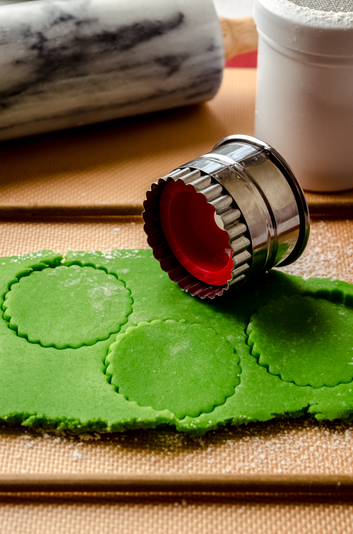 Grinch Linzer cookie dough on a surface with a Linzer cookie cutter sitting next to it.