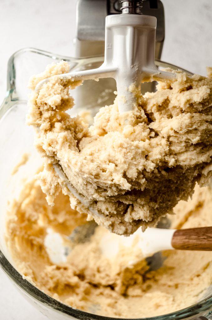 Linzer cookie dough in the bowl of a mixer fitted with the paddle attachment.